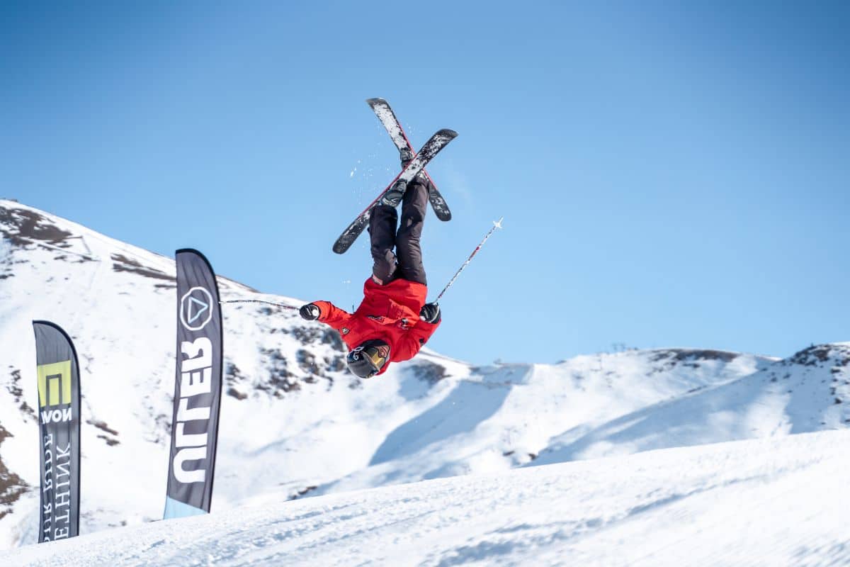 Esquiador realizando un backflip en el Snowpark de Boí Taüll con montañas nevadas de fondo.